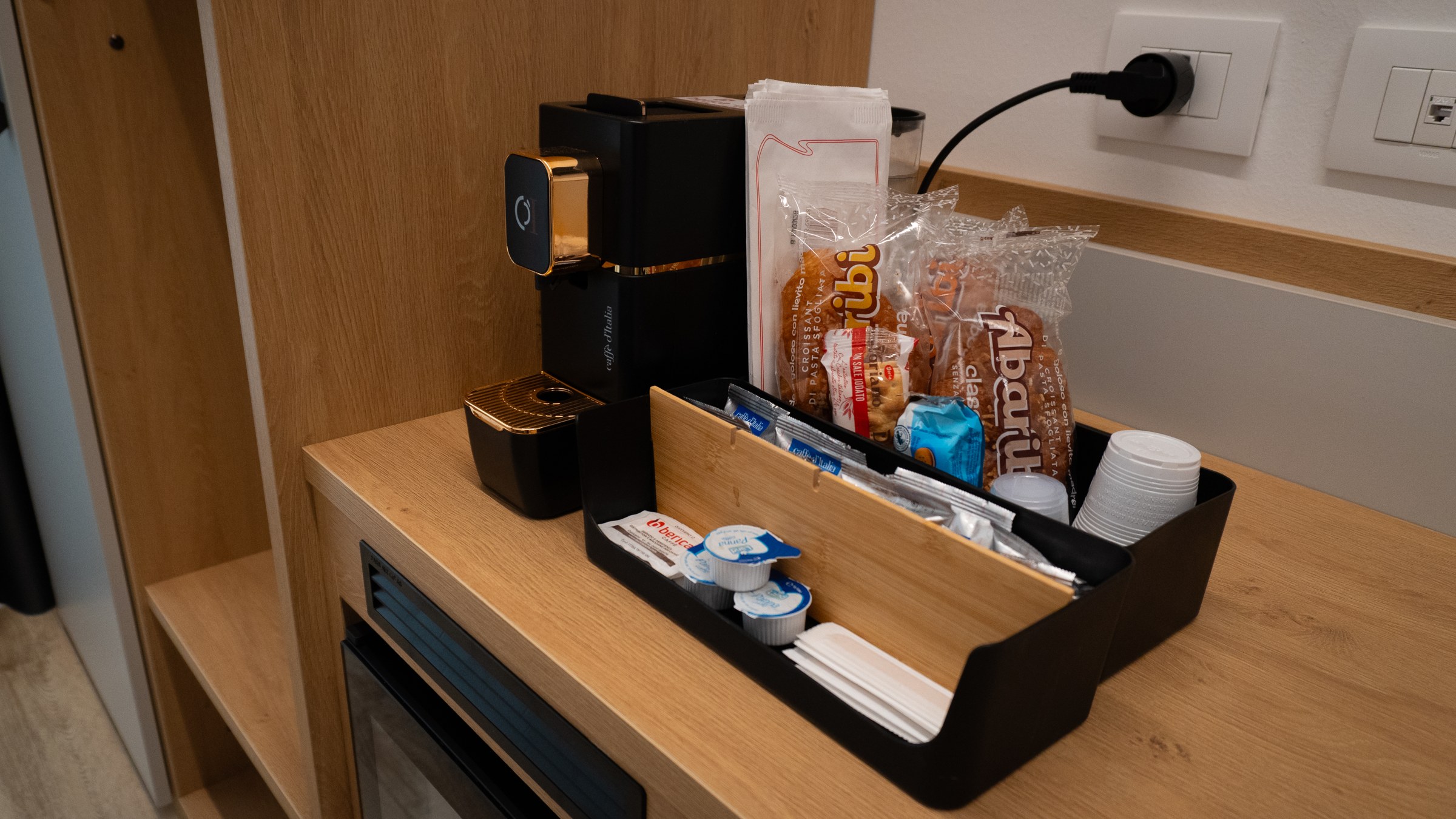 Angolo colazione in camera con macchina del caffè e prodotti confezionati